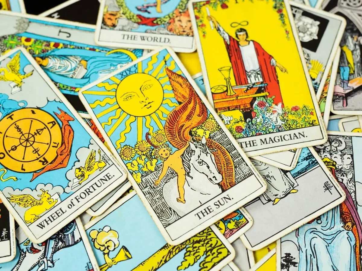Tarot cards scattered across a table: The Sun, The Magician, the Wheel of Fortune and The World