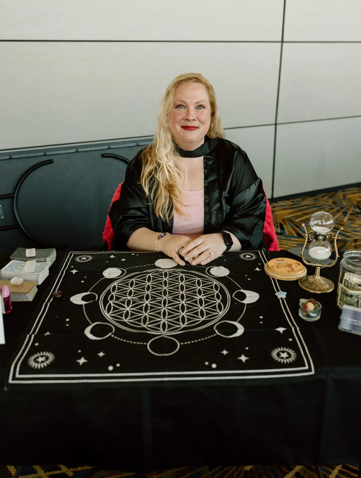 Danielle Rempala seated at her reading table, a Flower of Life cloth spread in front of her